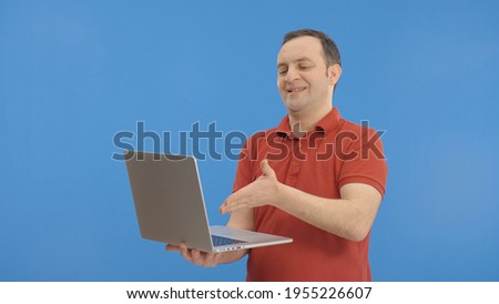 On a blue background, the young man is reading the news or mail on the computer. The man is very angry with the problem with the computer.