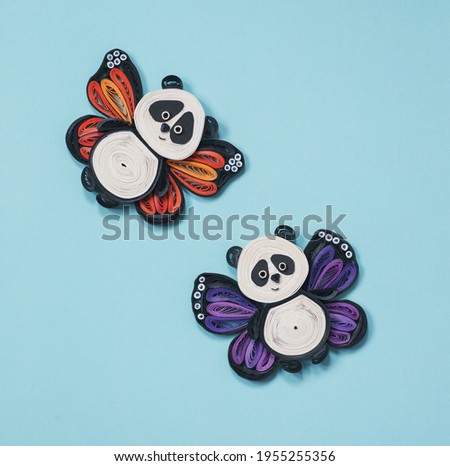 Happy cute panda flying in the sky. Two little pandas with butterfly wings. Happiness, dreaming and freedom concept. Hand made of paper quilling technique.