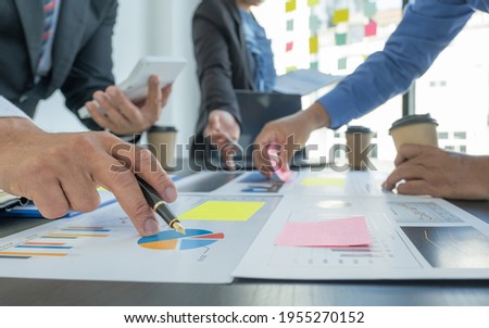 hand holding pen, businesswomen and businessmen team meeting to plan strategies to increase business income. Have a brainstorming finance graph analysis and discussing for the new target success. Royalty-Free Stock Photo #1955270152