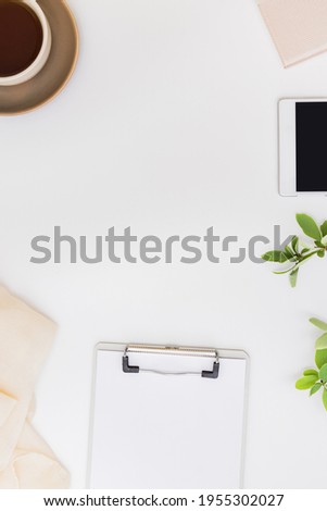 Flat lay home office desktop with notebook, clipboard, green leaves, cup with coffee on a white background
