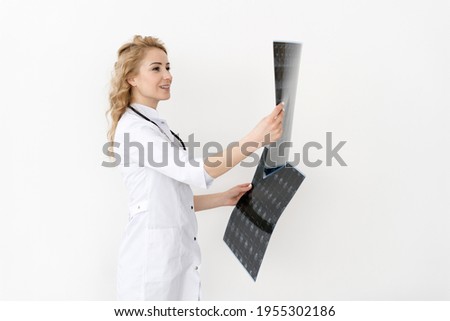 Woman doctor in white medical coat checking x-ray film, diagnose patient. Surgeon or nurse holding magnetic resonance scan of the brain, standing isolated on studio background with copy space