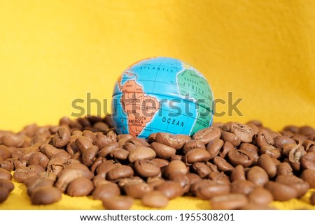 Coffee beans with a globe at the top, blurred. Concept coffee is the favorite drink of people all over the world in the morning. Yellow background