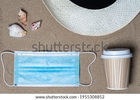Hat, coffee cup, seashells and medical mask, top view, there is a place for text. Summer vacation concept by the sea