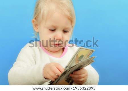 A small child is sorting out dollars on the table and looking at them intently.