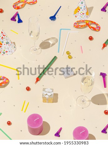 Candles and glasses with colorful party items on beige background. Birthday pattern. Minimal concept.