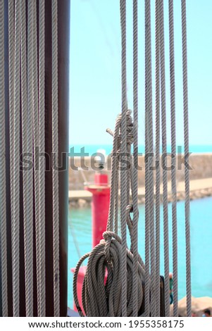 Views of a Mediterranean harbour from an old ship. With vertical ropes. Concept of navigation at sea.