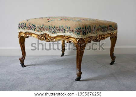 Antique footstool with gilt wood and needlework upholstered Royalty-Free Stock Photo #1955376253