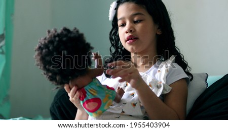 Hispanic mix race little girl child playing with black doll