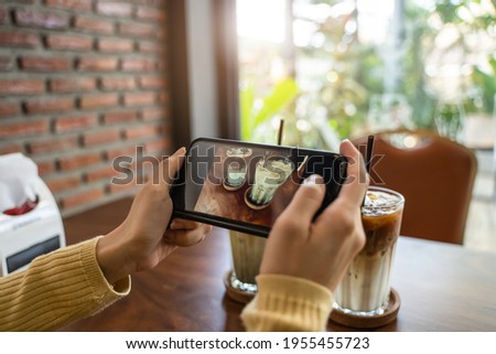 blogger use smartphone device taking a picture of coffee drink in cafe post into her blog