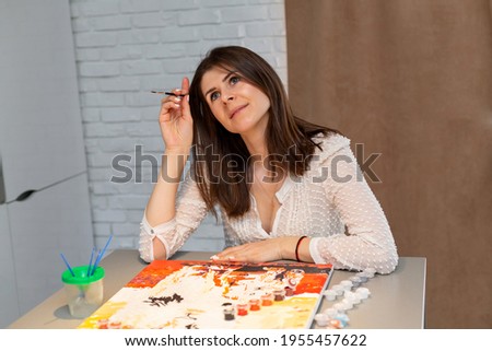 Portrait of a brunette painting a painting.