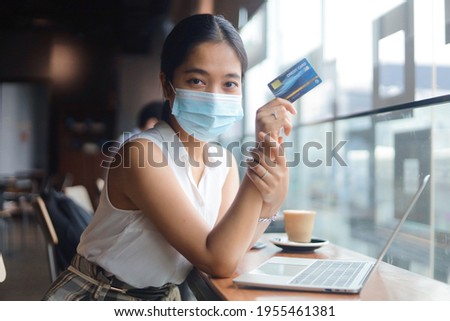 Portrait Woman wear medical face and holding credit card in hand.