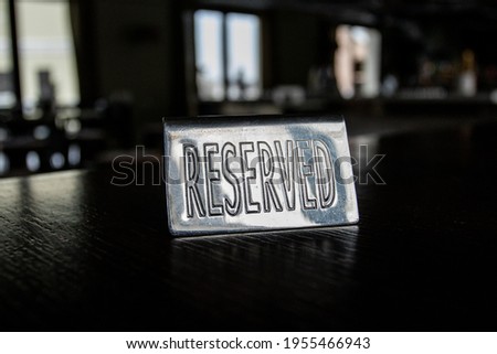 Metal plaque Reserved on the black table in a cafe against a background of blur and light in the windows. High quality photo