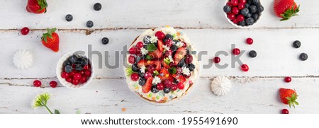Delicious homemade cake with fresh berries and mascarpone cream on wooden background. Top view, panorama, banner