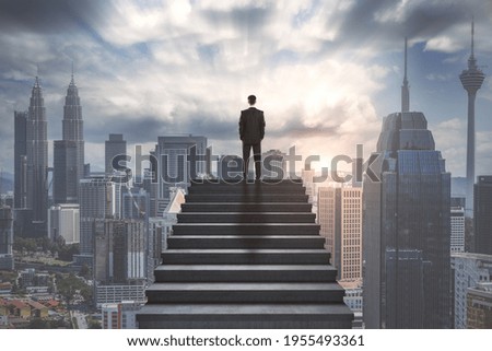 Ambition concept with confident businessman on the top of stairway and looking on city skyscrapers Royalty-Free Stock Photo #1955493361