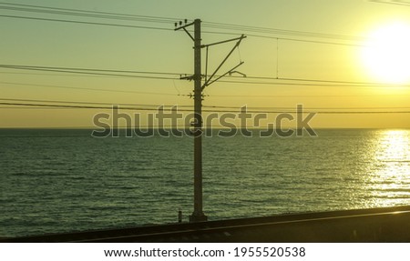 Poles with electric wires near the railway at sunset. 