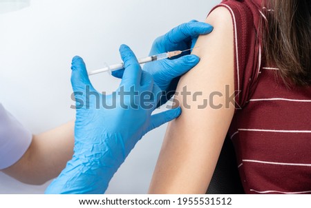 Close up of doctor or nurse giving shot of covid-19 vaccine to a patient's shoulder.