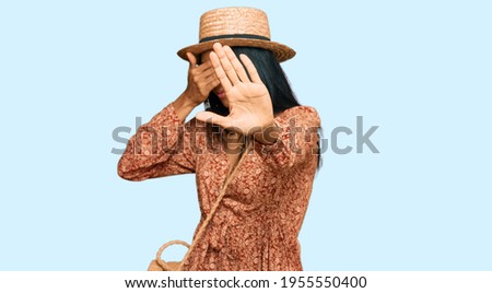 Young african american woman wearing summer hat covering eyes with hands and doing stop gesture with sad and fear expression. embarrassed and negative concept. 