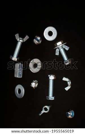 nuts, screws and washers falling on black background