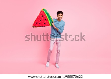 Full size photo of young excited afro man happy positive smile hold paper pinata watermelon slice isolated over pastel color background