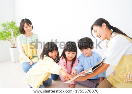 Nursery teacher and children reading a picture book