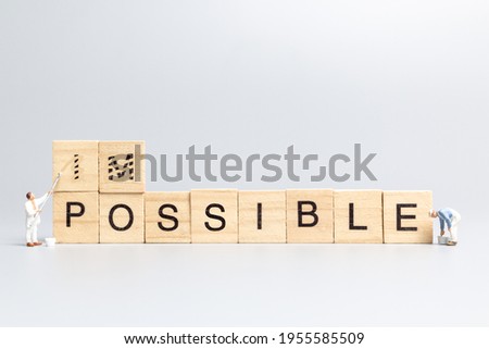 Miniature  people worker team on impossible word in wooden alphabet letters with prefix un crossed out, leaving the word possible Royalty-Free Stock Photo #1955585509