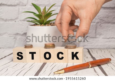 Hand putting coins on stack stair as step growing growth and wooden cube block with word STOCKS. Investment and save money concept.