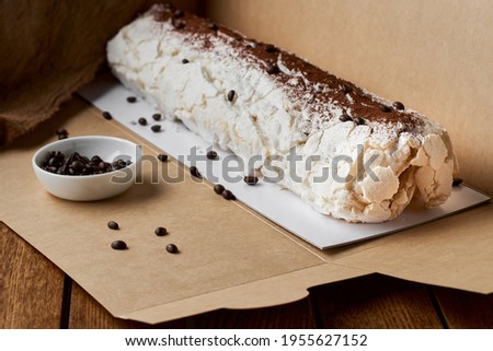 Close-up shot of meringue roll with coffee filling sprinkled with powdered sugar. Copy space, selective focus