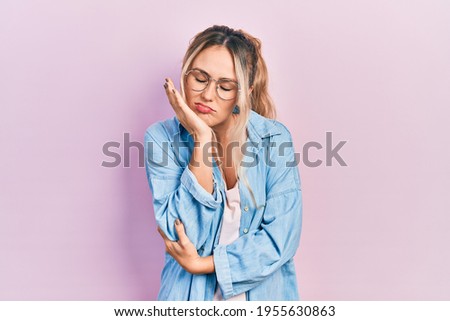 Beautiful young blonde woman wearing casual clothes and glasses thinking looking tired and bored with depression problems with crossed arms. 