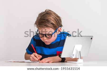 Portrait of preschool kid use tablet for online lesson to draw. Child doing homework by using digital tablet searching information on internet. E-learning or home schooling education concept.