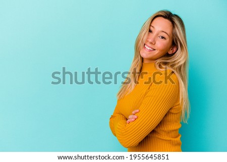 Young mixed race woman isolated on blue background smiling confident with crossed arms.