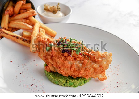 Fish and chips with mashed green peas and wasabi served with french fries on white background 