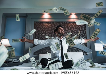 Successful businessmen celebrates success under money rain falling down dollar bills . Finances concept 