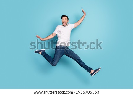 Full body photo of cheerful amazed young man jump up air raise hands isolated on pastel blue color background
