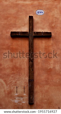 Wooden cross on orange old tabletop or wall surface
