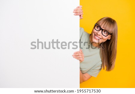 Close-up portrait of lovely cheerful girl holding copy space placard look idea ad isolated over bright yellow color background