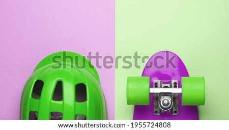 Cruiser board and safety helmet on pink green pastel background. Protective equipment for sports. Childhood. Top view