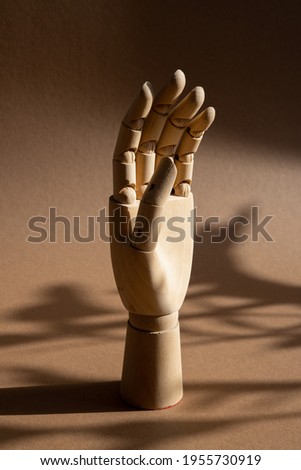 A hand of wood doll make fingers to touch, direct, move on brown background at the studio with dark shadows side view vertical