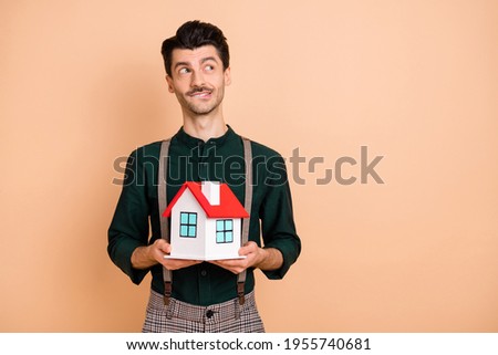 Photo of young man happy smile dream purchase new home relocation look empty space isolated over beige color background