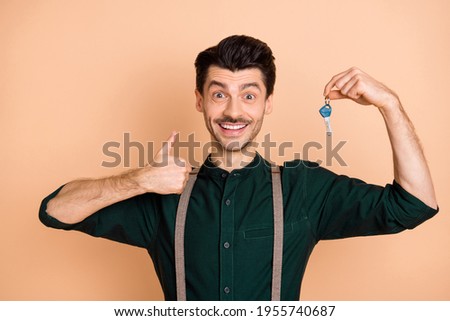 Photo of young man happy smile show thumb-up like choice buy new property keys isolated over beige color background