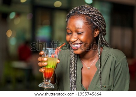 image of beautiful african lady, holding a glass of cocktail with excitement