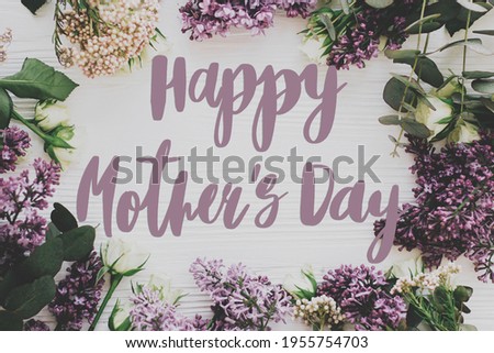 Happy mother's day. Happy mother's day text and lilac and roses frame flat lay on white wood. Stylish floral greeting card. Handwritten lettering. Mothers day