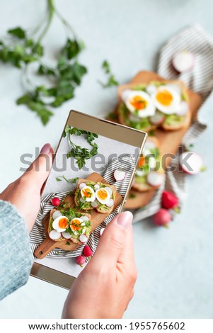 Woman doing snapshot of her healthy avocado and egg toasts for breakfast