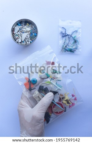 Stock photo of different pieces of plastic and microplastics inside a sample bag next to microplastic fibers