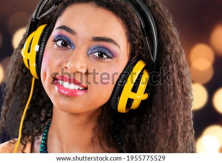 Fashion hipster girl smiles and wear headphones listening to music over background