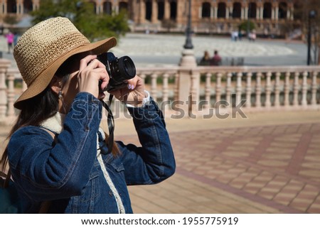 Young and beautiful asian tourist taking photos of monument with reflex camera during her vacation trip.