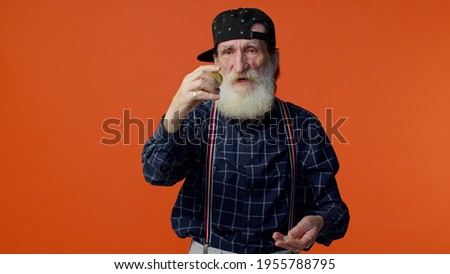 Mature old bearded stylish grandfather showing golden bitcoins. Achievement career wealth, cryptocurrency investment, mining, future technology. Senior man on orange background. People businesspeople