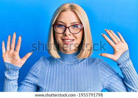 Young blonde woman wearing casual clothes and glasses showing and pointing up with fingers number ten while smiling confident and happy. 