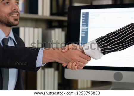 businesswoman shake hands with young businessman after signing contract in office