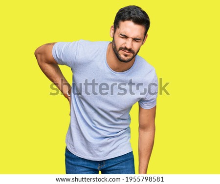 Young hispanic man wearing casual clothes suffering of backache, touching back with hand, muscular pain  Royalty-Free Stock Photo #1955798581
