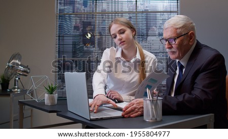 Woman secretary talking on mobile cell phone with client. Busy senior business man boss entrepreneur working, analysis financial graph data in office. Girl having conversation on telephone. Team work